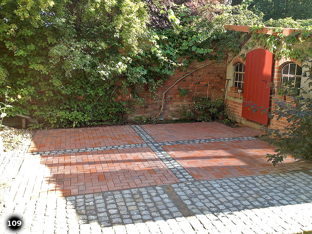 Platz vor einem Haus mit roten versetzten Steinziegeln und grauen kleinen Pflastersteinen