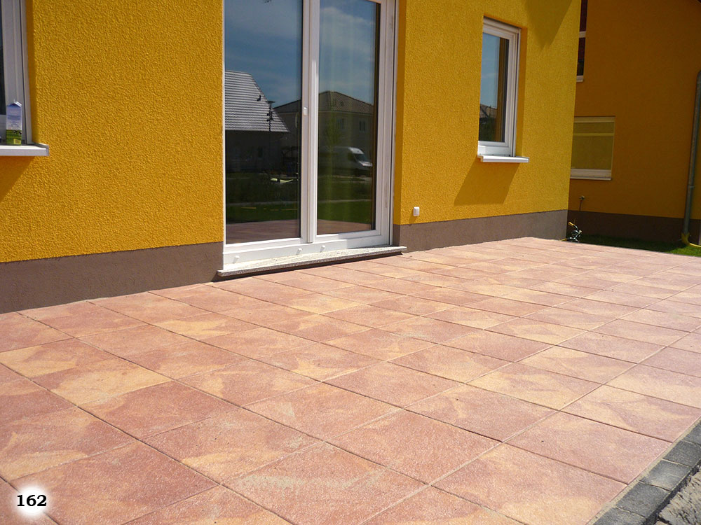 Moderne mit einem schicken Muster versehende Betonsteinplatten vor einem gelben Haus