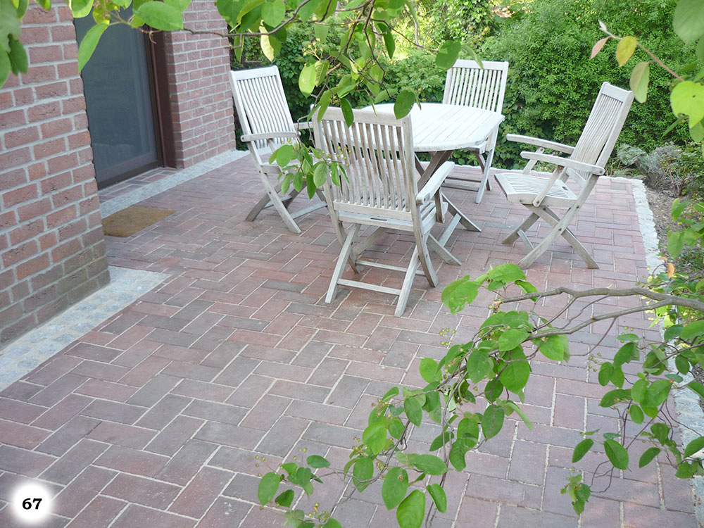 Terrasse mit einem Boden aus verwinkelten Betonsteinen, Tisch und Stühlen