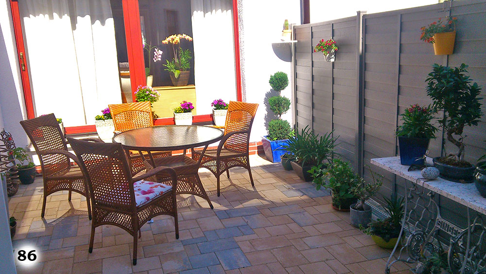 Eine schicke Terrasse mit einem Tisch, Stühlen mit einem Sichtschutz