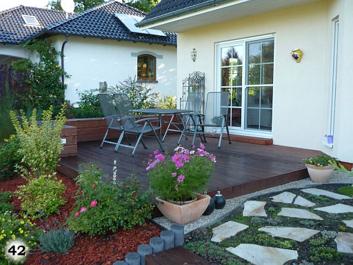 Dunkle Terrasse vor einem Haus mit Pflanzen und einer Sitzmöglichkeit
