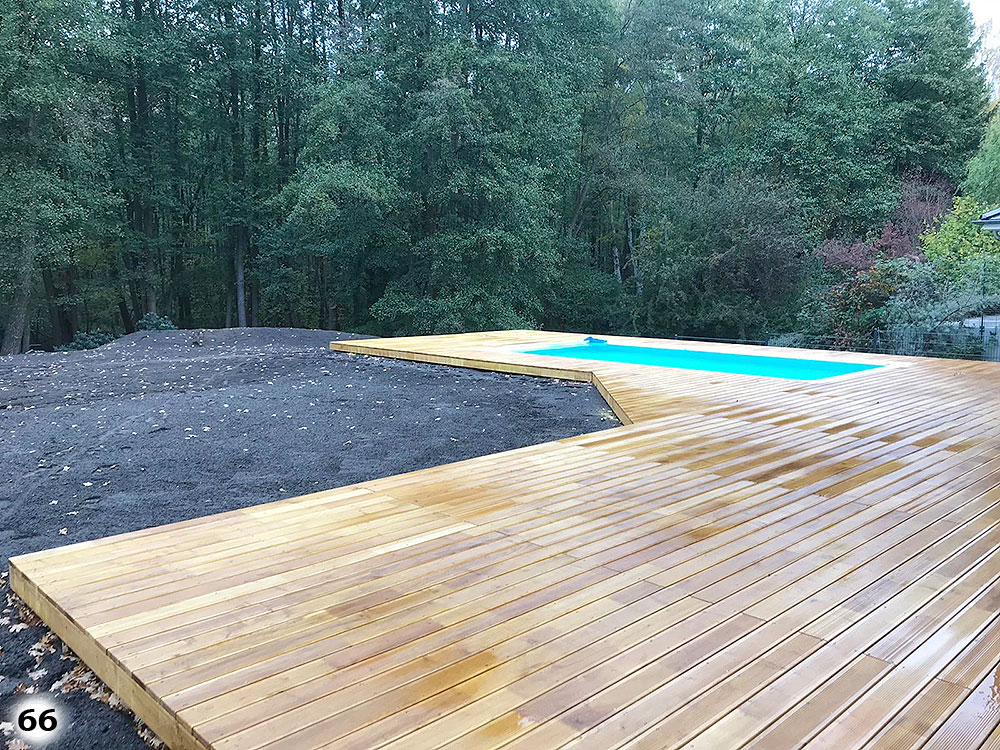 Ein großer Holzboden mit einem kleinen Pool an einem Wald angrenzend