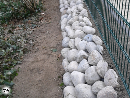 Eine Steigung aus hellen Steinen zu einem Zaun