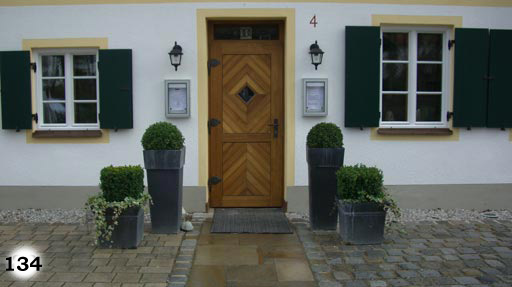 Vorhof aus kleinen, grauen, quadratischen Pflastersteinen mit Weg zur Eingangstür aus braunen, unterschiedlich großen Steinplatten