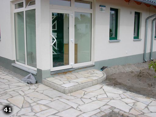 Stufe vor Tür aus nicht symmetrischen Steinplatten auf Weg aus nicht symmetrischen Steinplatten