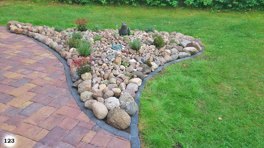 Eine Ecke einer Terrasse belegt mit vielen unterschiedlich großen Steinen