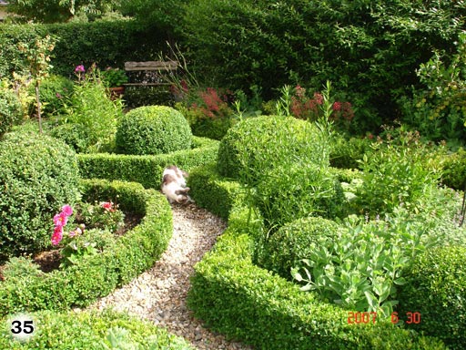liebevoll angelegter, schöner, grün blühender Garten, mit schmalen Wegen aus Kieselsteinen
