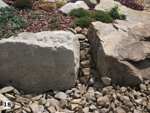 Lücke zwischen zwei großen Steinen mit vielen kleinen Steinen. Große Steine mit Holzspäne und Moos