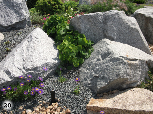große, weiße Steine, restliche Flächen aufgefüllt mit grauen Kieselsteinen und Blumen