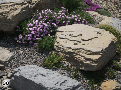 große Steine mit Blumenbeflanzung und Holzpäne