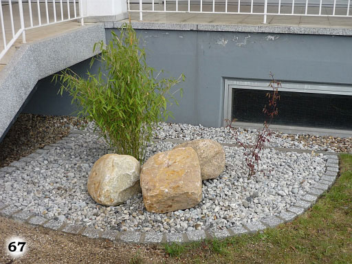 Ein Bereich mit 3 großen Steinen, einer großen Pflanze und  mit kleinen Kieselsteinen