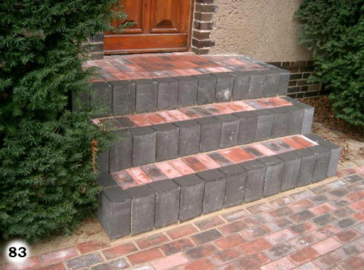 Einfache Ziegelsteintreppe mit grauen Steinen umrandet vor einem Hauseingang