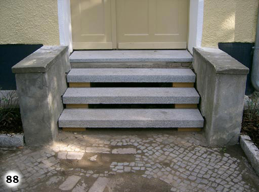 Treppe mit in der Luft hängenden Stufen und grauen Steingeländern for einem Hauseingang