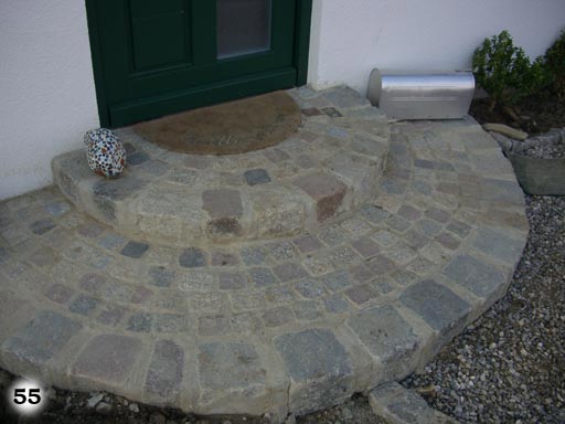 Elegant runde Stufen aus Pflastersteinen mit einer vor dem Hauseingang Fußmatte oben drauf