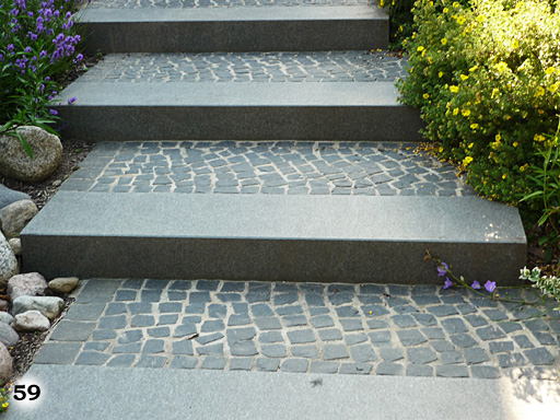 Eine schräge Treppe welche vorne eine lange graue Stufe hat und dahinter viele kleine rote Ziegelsteine