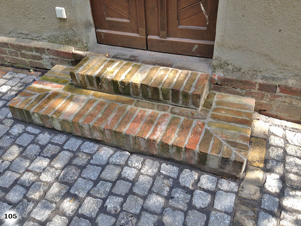 Stufen aus Ziegelsteine vor einer braunen Haustür