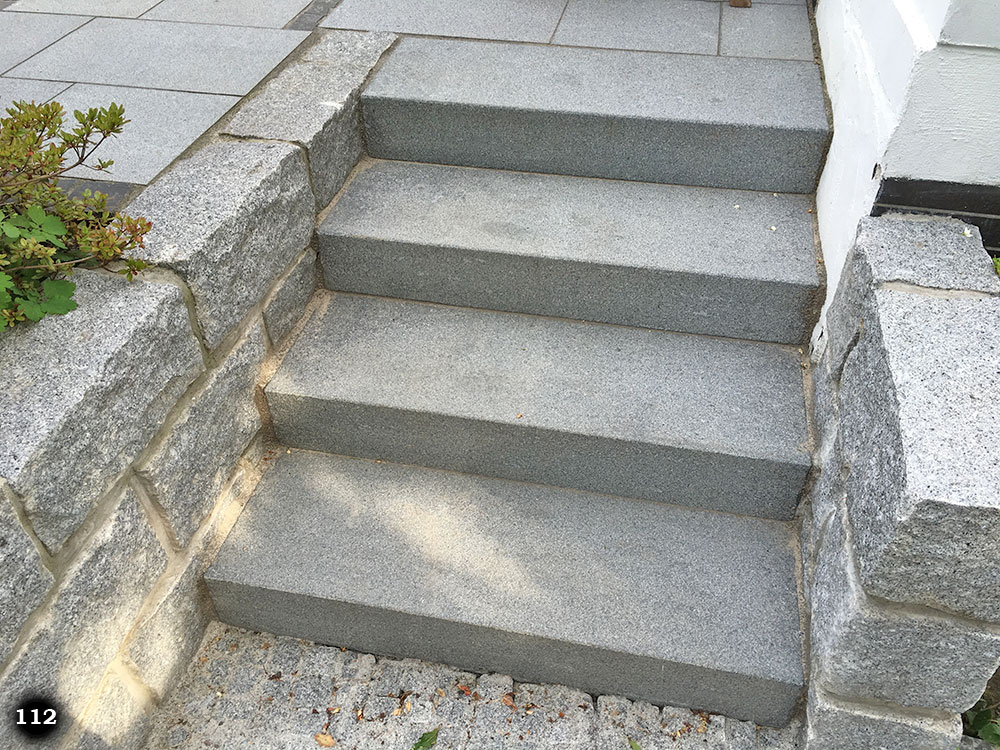 Eine graue schmale Treppe mit grauen Mauerwerk als Geländer
