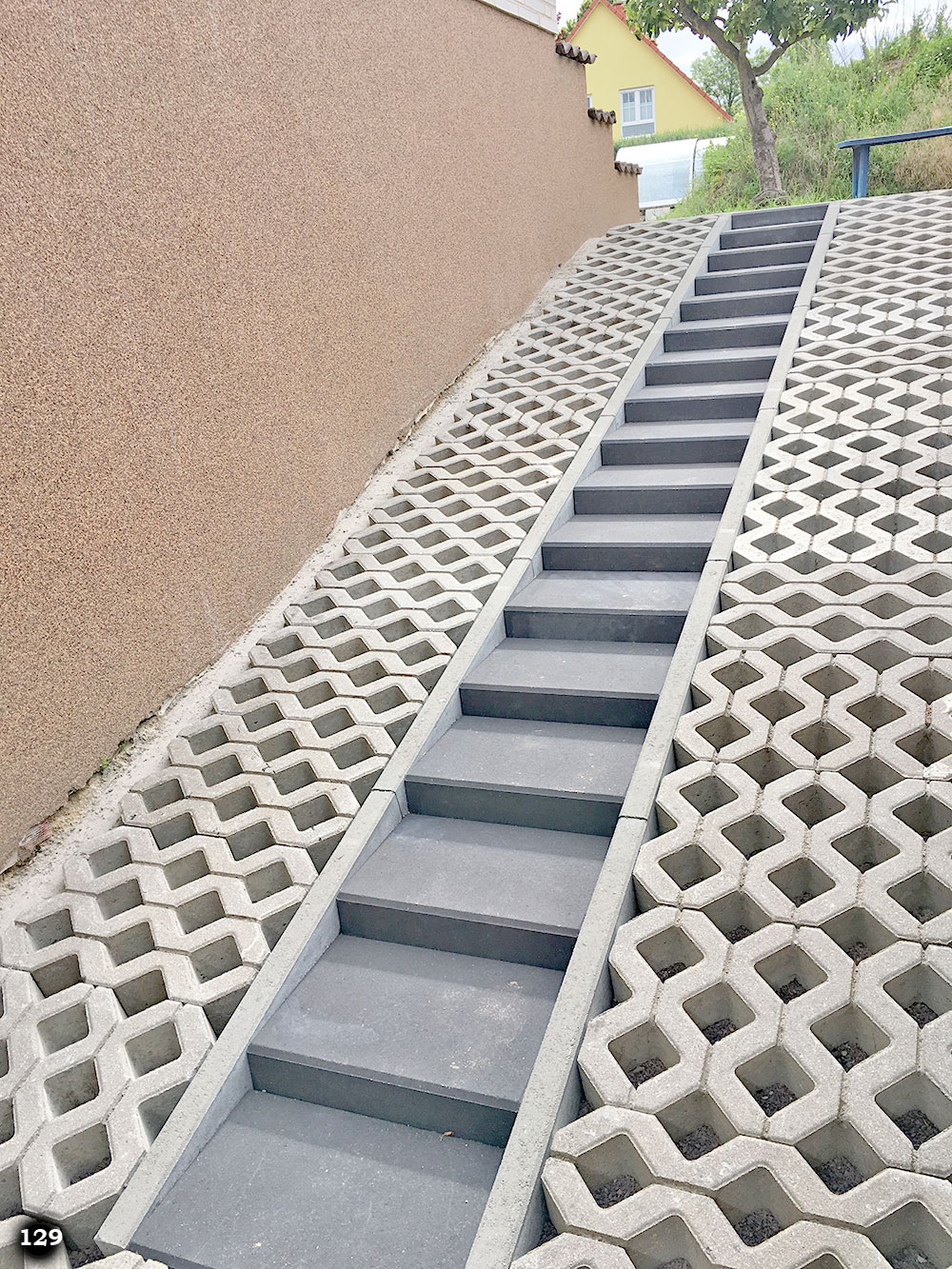 Eine steile schmale Treppe mit langen Stufen an einer Mauer