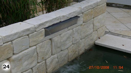 Eine Mauer aus der Wasser in einen kleinen Teich läuft