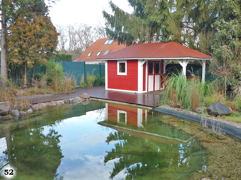 Ein Teich neben einem Rot weißen Haus, mit einigen Pflanzen drum herum